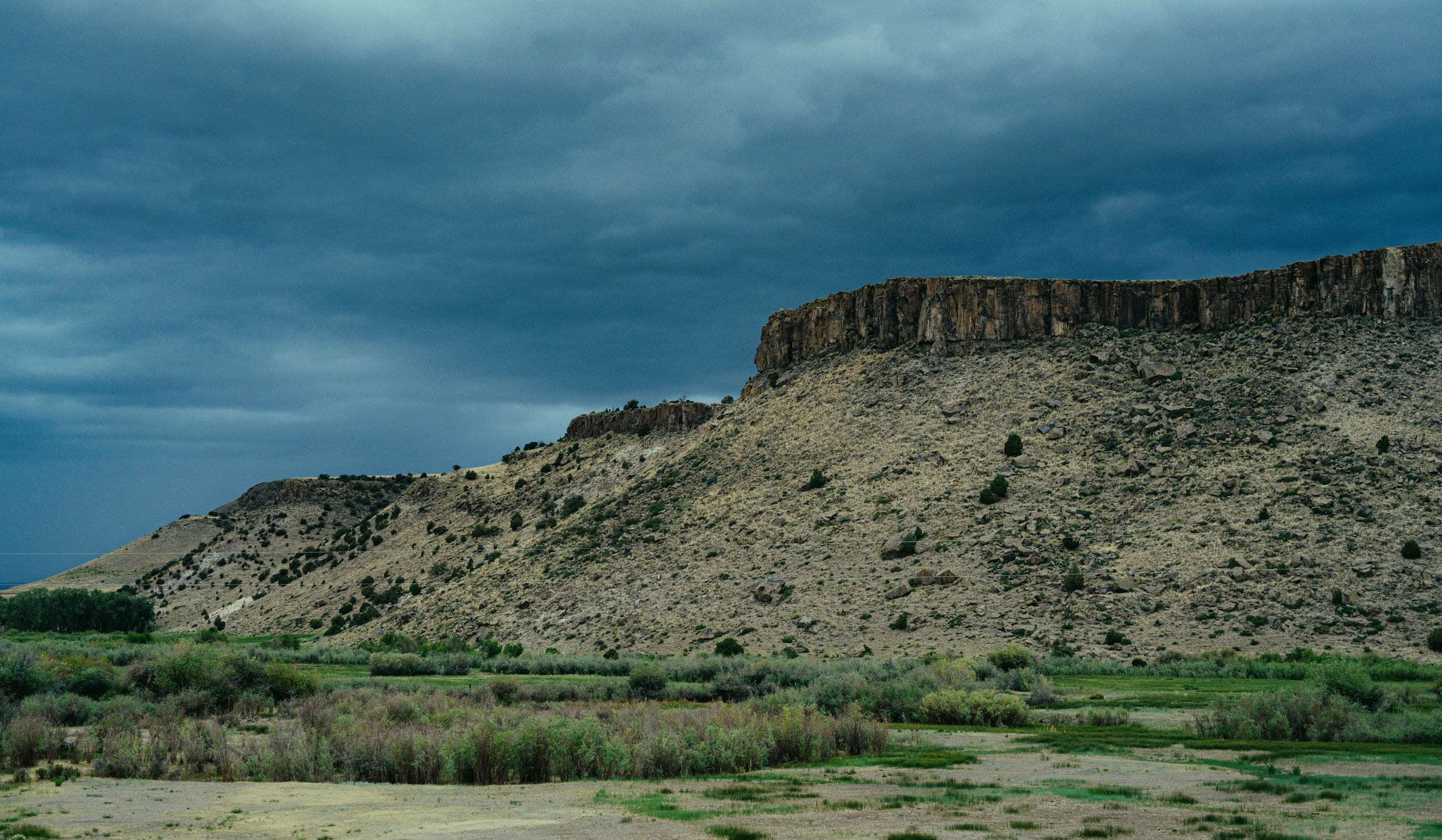 Flat-topped mesa above green fields near Clifton, CO