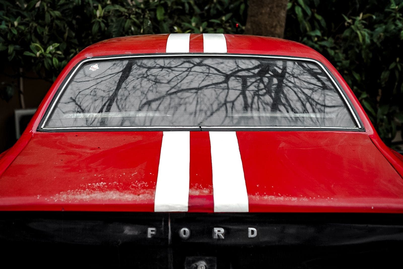 Rear window of a red car with white racing stripes