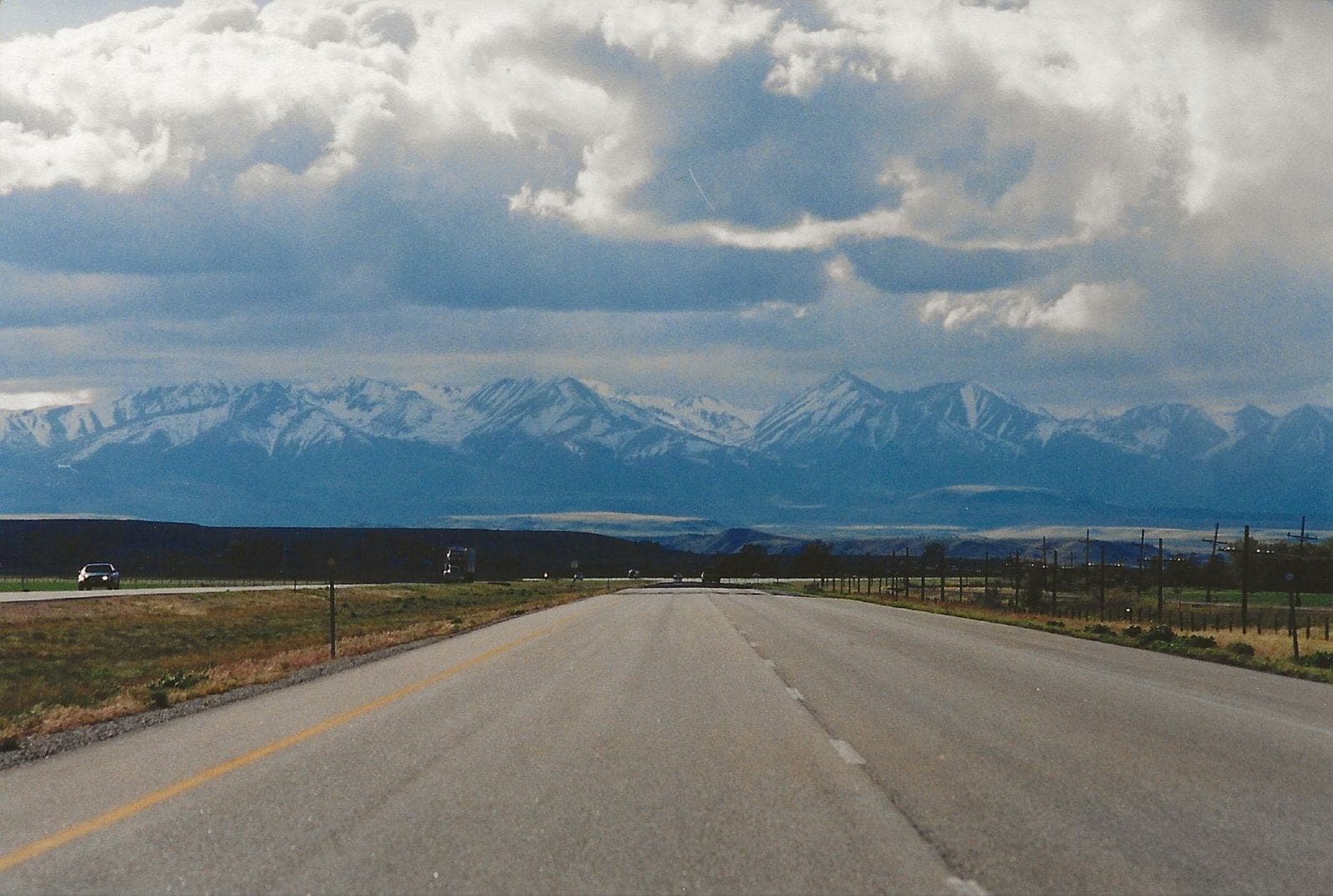 Highway toward snowy mountains under heavy clouds