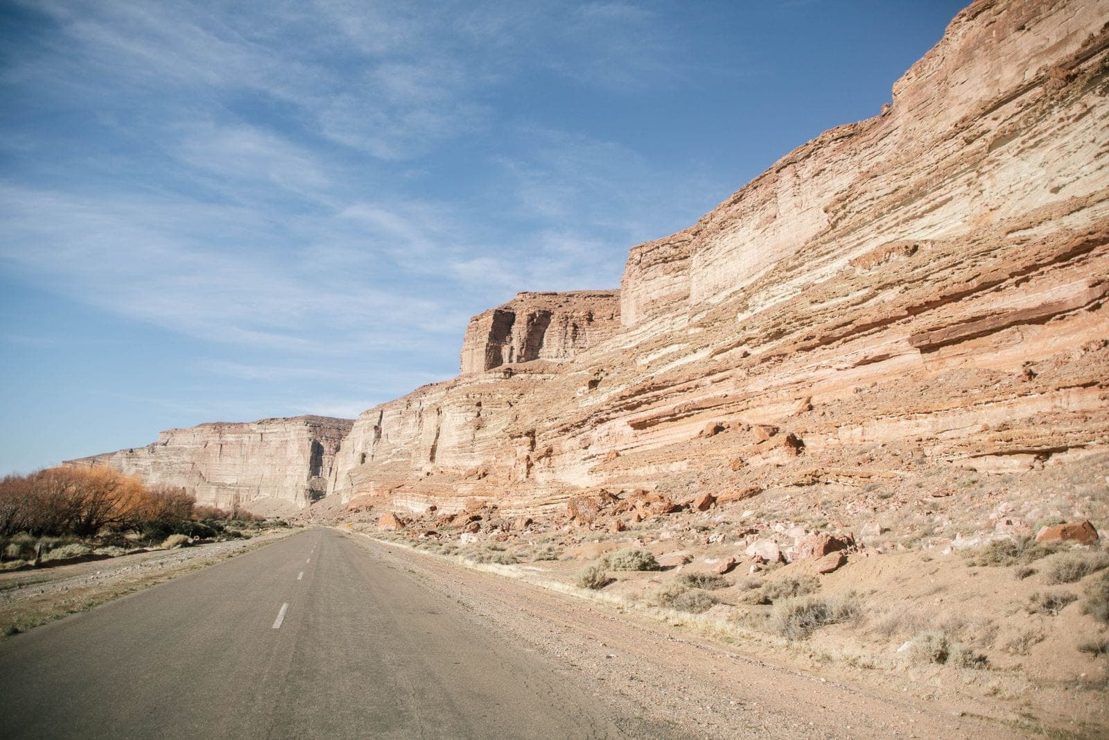 Road running beneath layered sandstone cliffs