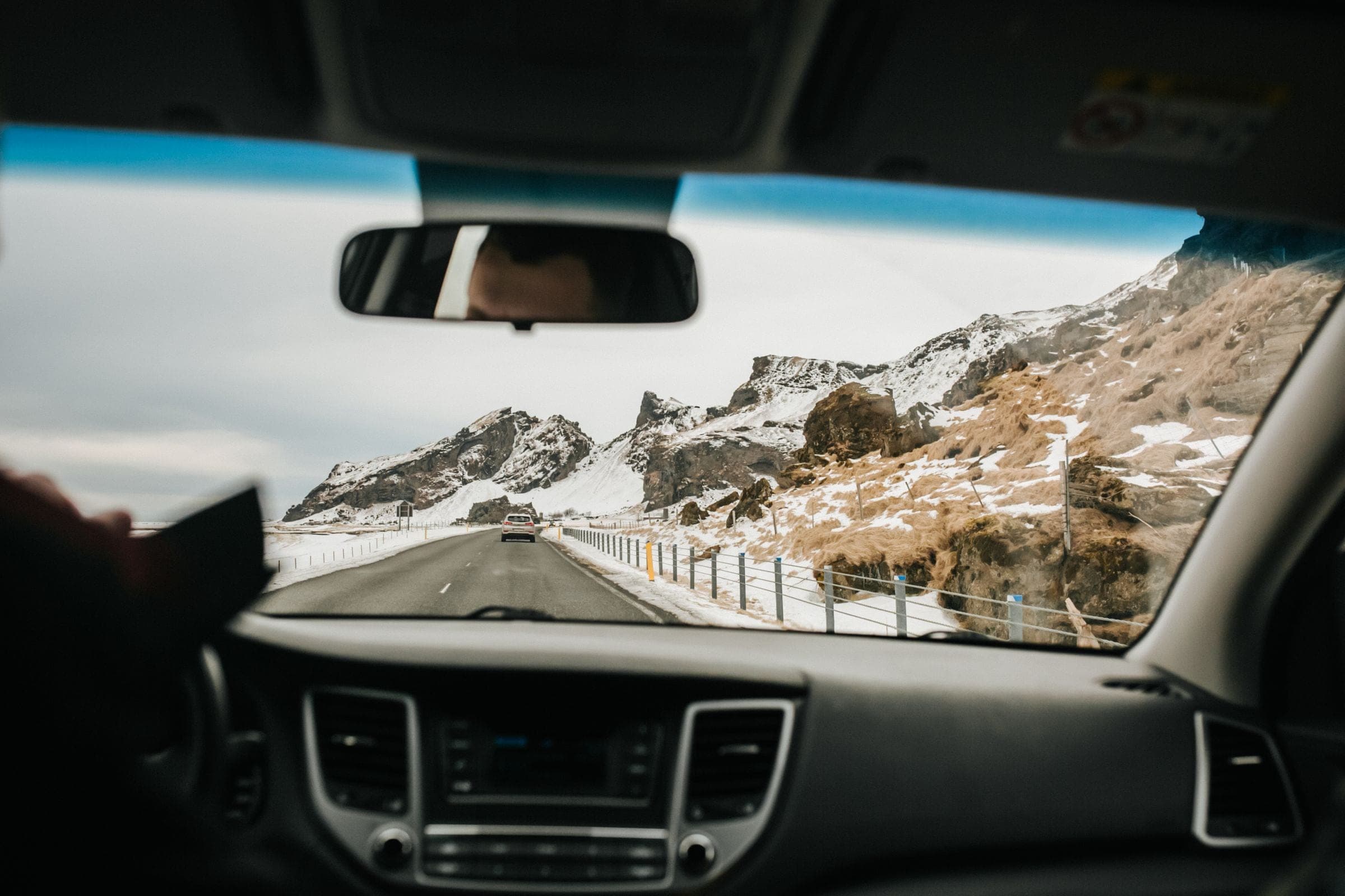 View through a windshield with the mirror and camera mount on a mountain road