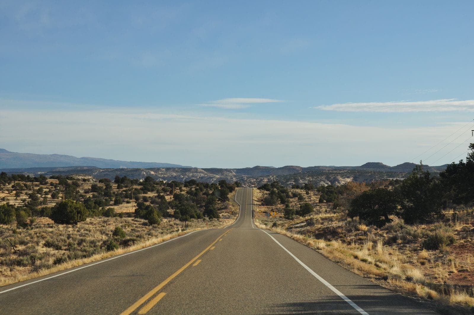 Two-lane highway crossing desert toward distant mountains
